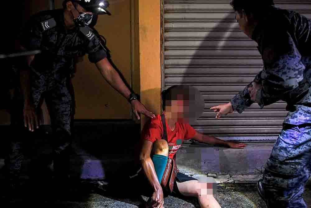 Anggota penguat kuasa imigresen menahan wanita warga asing yang tercedera selepas terjun dari tingkat dua sebuah bangunan bagi mengelak dicekup dalam operasi di sekitar rumah kedai di Seremban 2, tengah malam tadi. Foto Bernama