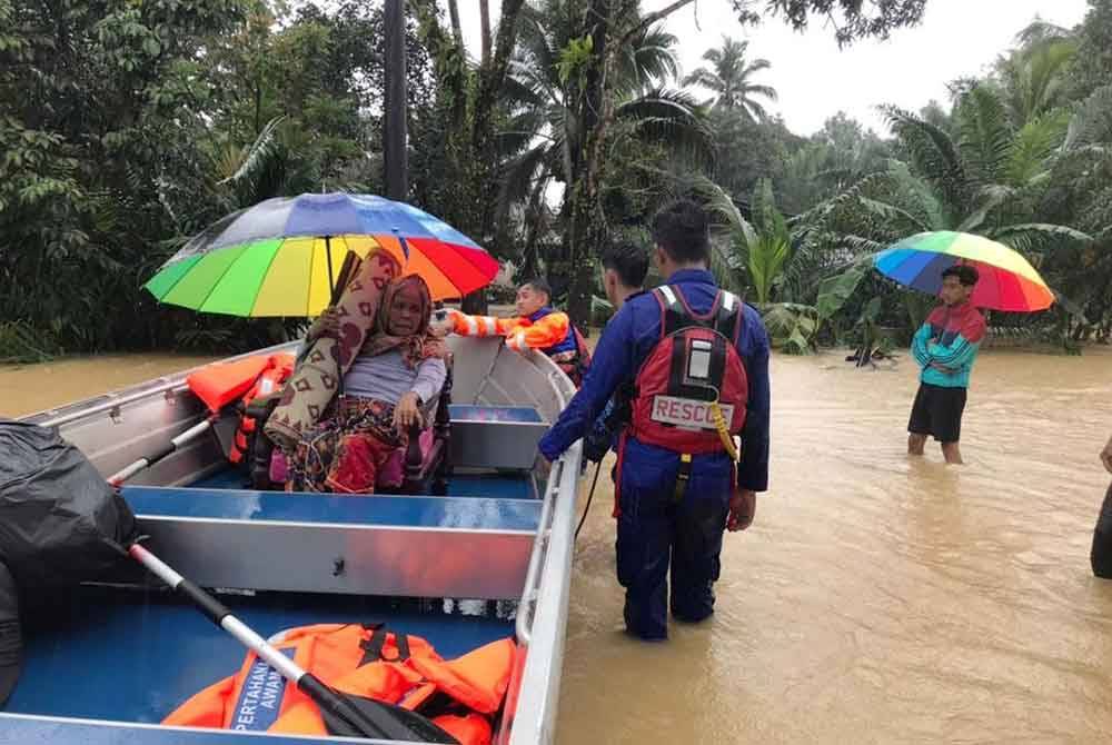 Anggota penyelamat membantu memindahkan warga emas di Kampung Hulu Seladang, Setiu ke PPS berdekatan. FOTO: APM