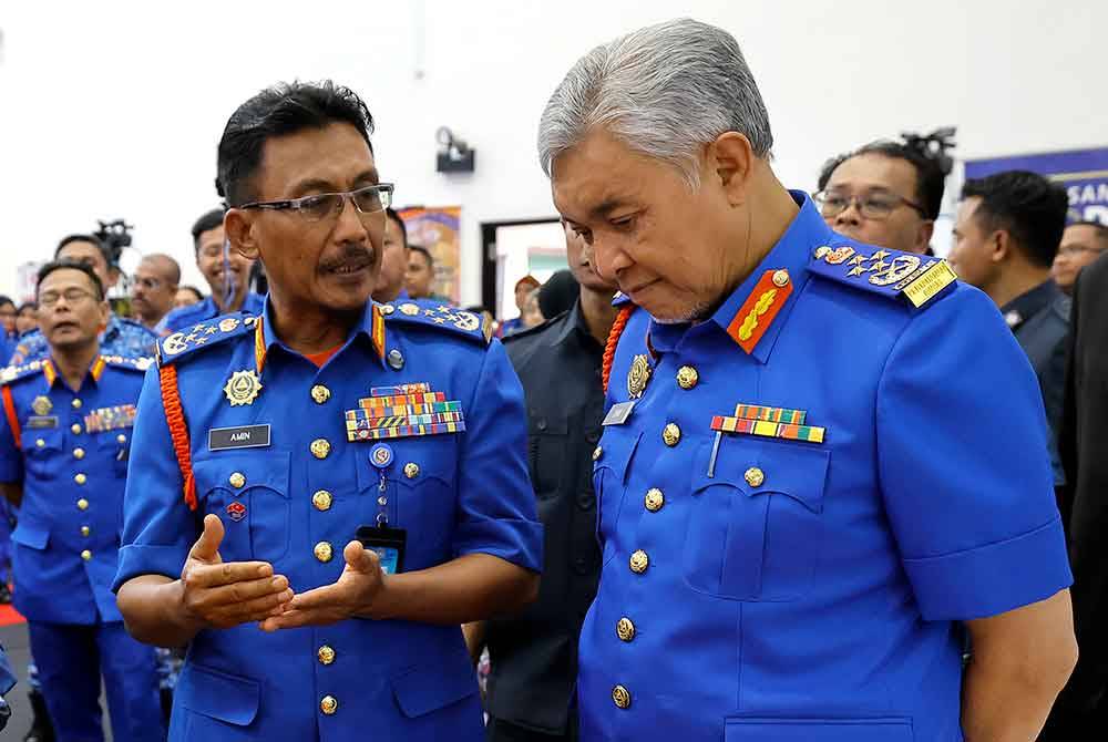 Timbalan Perdana Menteri Datuk Seri Dr Ahmad Zahid Hamidi bersama Ketua Pesuruhjaya Angkatan Pertahanan Awam Malaysia Datuk Aminurrahim Mohamed (depan, kiri) semasa mengadakan lawatan kerja di Ibu Pejabat Angkatan Pertahanan Awam Malaysia (APM) pada Rabu. Foto Bernama