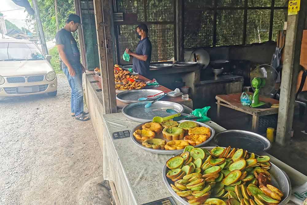 Mohd Nurdin (kanan) melayan pelanggan yang datang membeli kuih di gerainya yang beroperasi di Kampung Padang Tengir, Manir di Kuala Terengganu.
