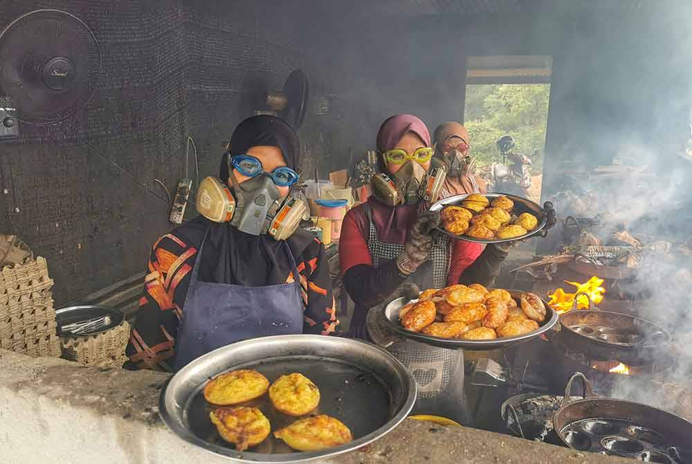 Raja Nurul Wahida (kiri) menunjukkan kuih tradisional akok yang siap dibakar dan sedia untuk dijual kepada pelanggan.