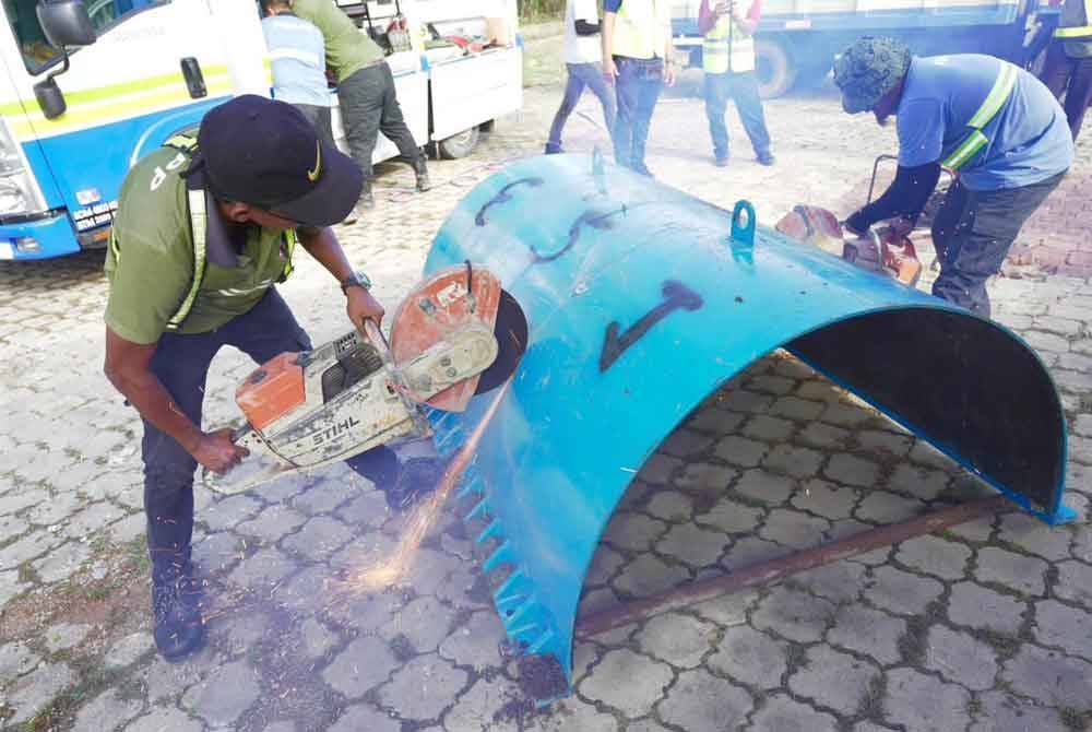 Pekerja sedang menjalankan Pelan A iaitu memotong bahagian bawah pengapit berat kepada beberapa bahagian untuk memudahkan pengikatan pada paip bawah air yang bocor. - Foto Facebook PBAPP