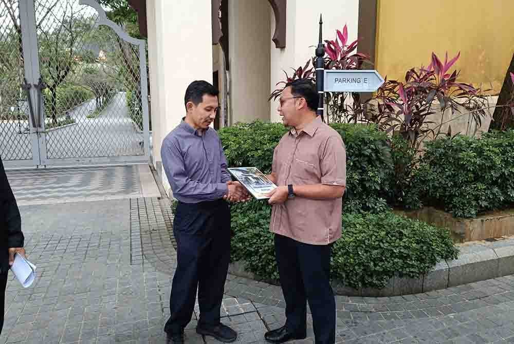 Kamarul Azizan (kiri) menyerahkan memorandum kepada wakil istana di hadapan pintu di Istana Syarqiyyah.