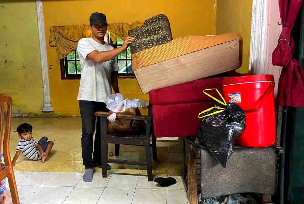 Air sudah surut, Fauzi guna peluang ini untuk mencuci dan mengemas rumahnya di Kampung Batu Hitam, Pasir Puteh pada Khamis.