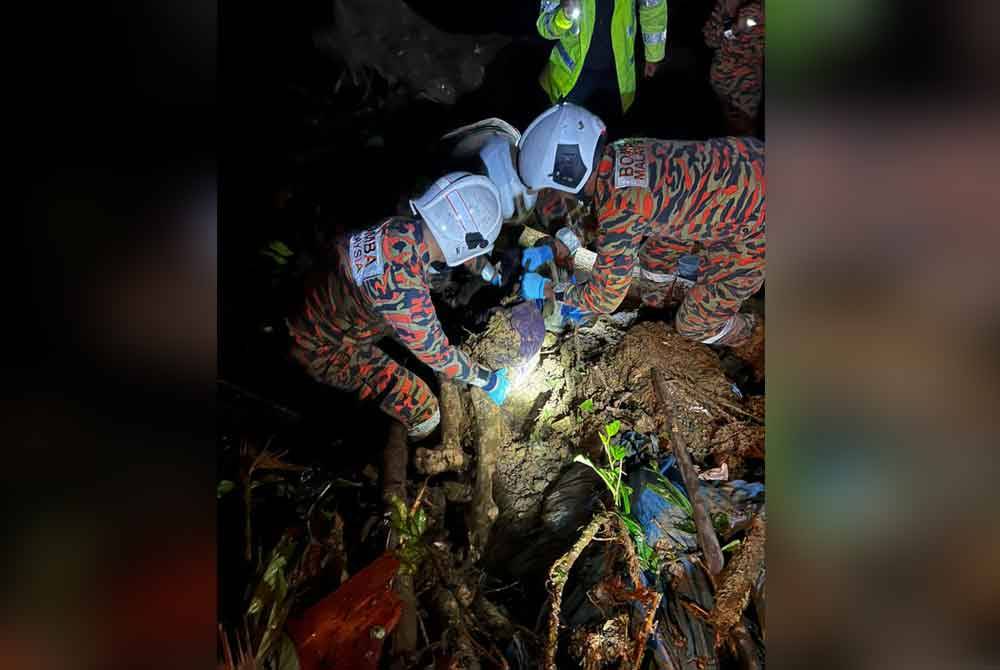 Anggota bomba dari BBP Cameron Highlands membantu mengeluarkan salah seorang mangsa yang ditemui tertimbus dalam kejadian tanah runtuh di Cameron Highlands pada Jumaat.