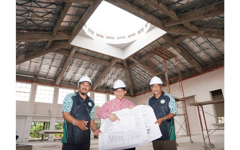 Mohd Sharif (tengah) menunjukkan pelan Masjid Saujana Puchong yang tertangguh pembinaan disebabkan faktor dana kewangan. 