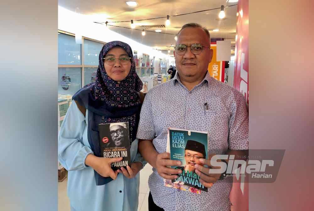 Azian (kanan) bersama isterinya menunjukkan buku yang menarik minat mereka.
