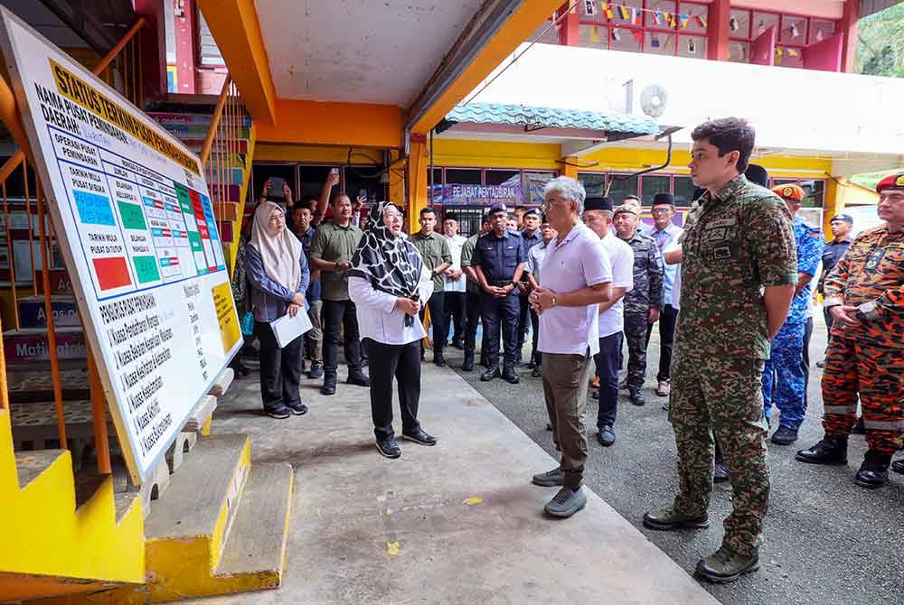 Al-Sultan Abdullah Ri'ayatuddin Al-Mustafa Billah Shah berkenan mendengar taklimat yang disampaikan Pegawai Daerah Kuantan, Datuk Aida Munira Abdul Rafar (dua dari kiri) semasa mencemar duli melawat PPS SMK Sg Lembing pada Sabtu. - Foto Bernama