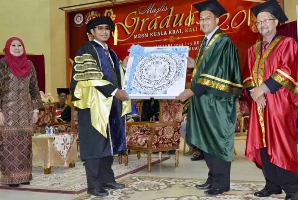 Nik Mohd Khairuddin (dua dari kiri) menerima cenderamata disampaikan oleh Pengetua MRSM Kuala Krai, Ismail Deraman (dua dari kanan).