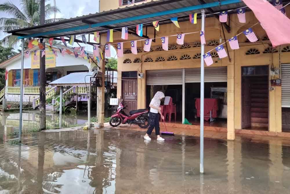 Nurdiana membersihkan kawasan restoran yang digenangi air akibat hujan lebat.