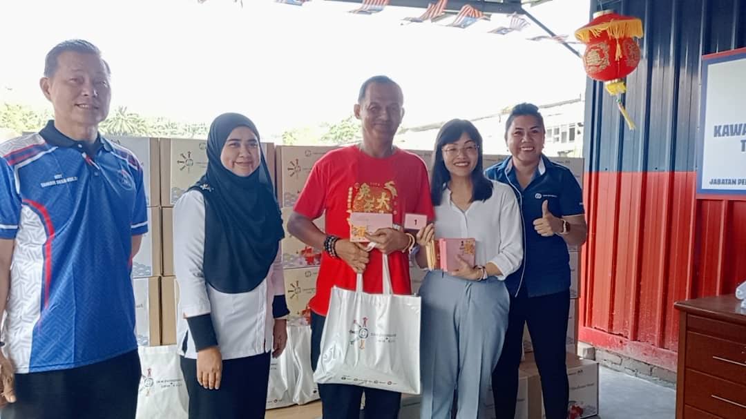 Nie Ching (dua dari kanan) menyampaikan sumbangan kepada penerima sempena program CSR Environment Kasih dan Misi Sampul Merah di Taman Desa, Kulai pada Ahad