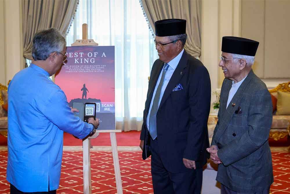 Yang di-Pertuan Agong, Al-Sultan Abdullah Ri’ayatuddin Al-Mustafa Billah Shah berkenan mengimbas kod QR pada gimik pelancaran e-book bertajuk 'Test of A King' di Istana Negara pada Ahad. Foto Bernama