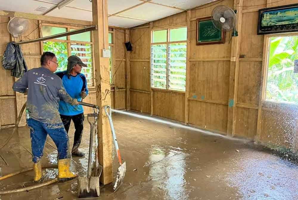 Hanafiah (kiri) sedang melakukan kerja pembersihan banjir. Foto Facebook Hanafiah Mat