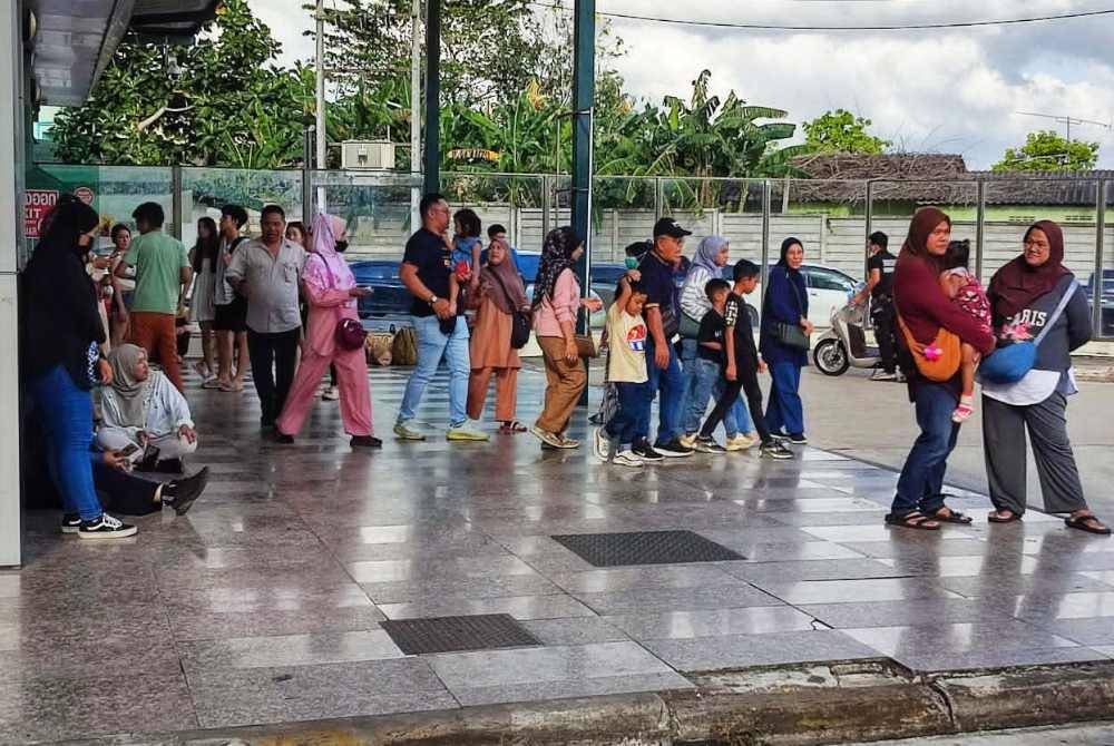 Pelancong yang berkunjung ke Thailand terpaksa berdiri dan duduk di tepi bangunan di CIQ Thailand sementara menunggu proses pemeriksaan Imigresen oleh pemandu kenderaan.