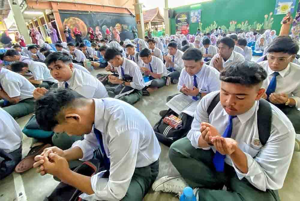 Sebahagian calon berdoa sebelum menduduki peperiksaan bertulis SPM di SMK Rahmat, Kuala Sungai Baru, di sini, pada Selasa.