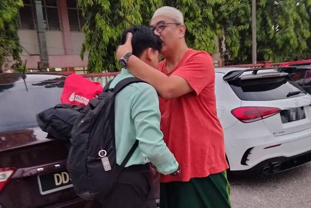 Mohamad Iman Afiq dipeluk bapanya sebelum memasuki dewan peperiksaan