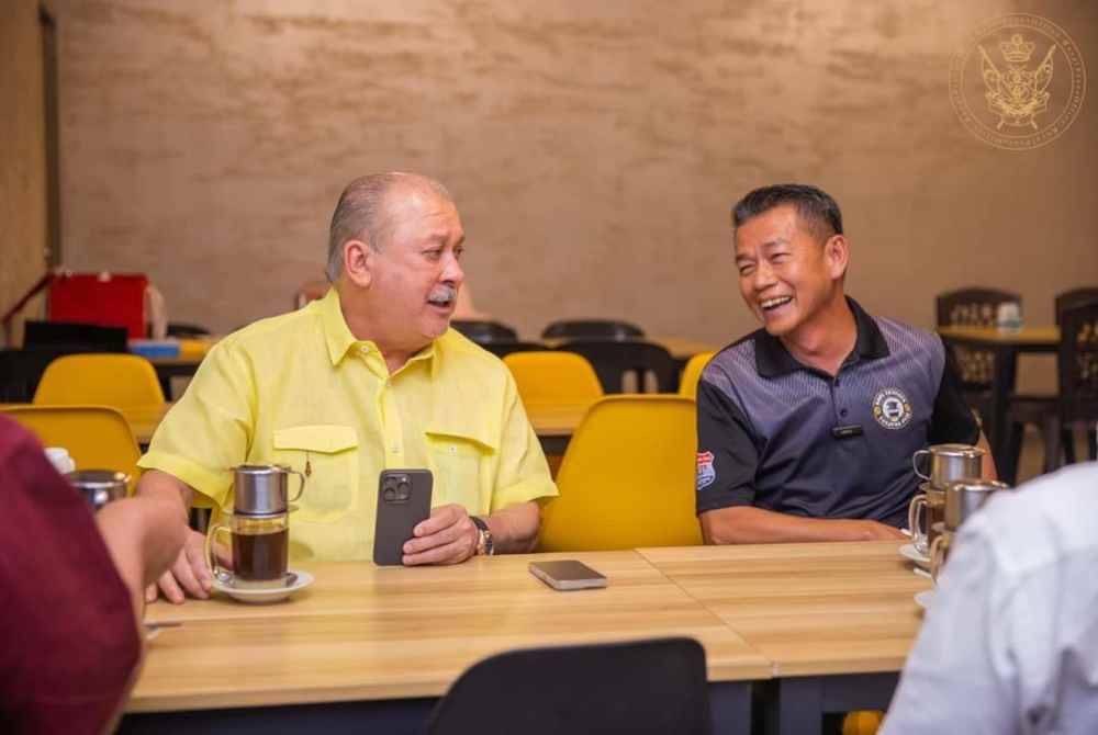 Ghazali duduk disebelah Sultan Ibrahim ketika baginda mengunjungi kafe Kopi Tenggek Tanjung Piai pada Mac tahun lalu.