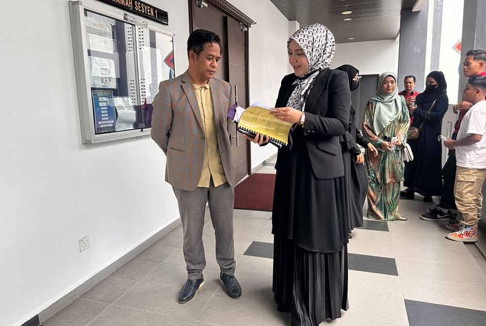 Mohammad Yusri (kiri) berbincang dengan peguam, Azura Ghazali (kanan) di luar bilik mahkamah.