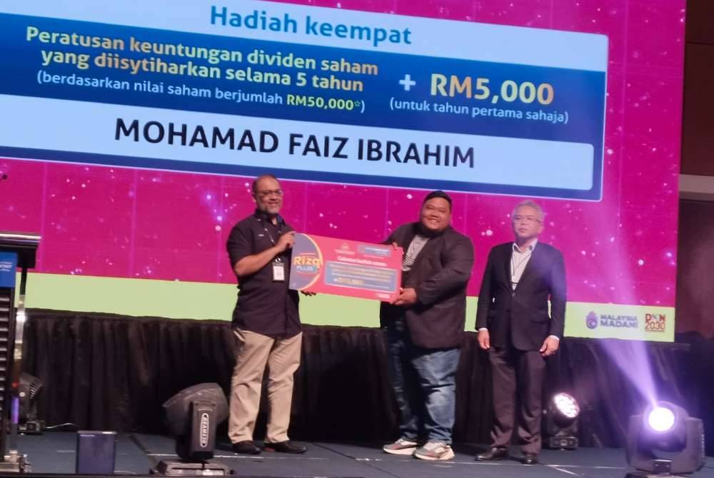 Mohd Faiz (tengah) menerima hadiah daripada Bank Rakyat pada Majlis Pengumuman Jutawan Pertama Akaun Pelaburan i-Rizq Plus di Menara Kembar Bank Rakyat.
