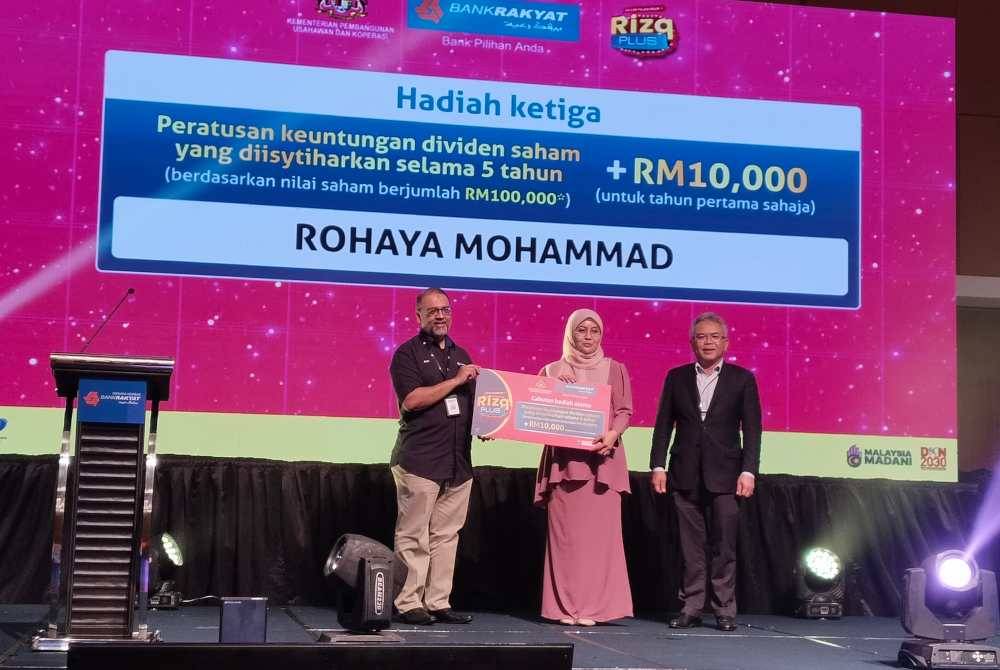 Mohd Irwan (kiri) menyerahkan hadiah kepada pemenang ketiga, Rohaya (tengah) pada Majlis Pengumuman Jutawan Pertama Akaun Pelaburan i-Rizq Plus di Menara Kembar Bank Rakyat pada Rabu.