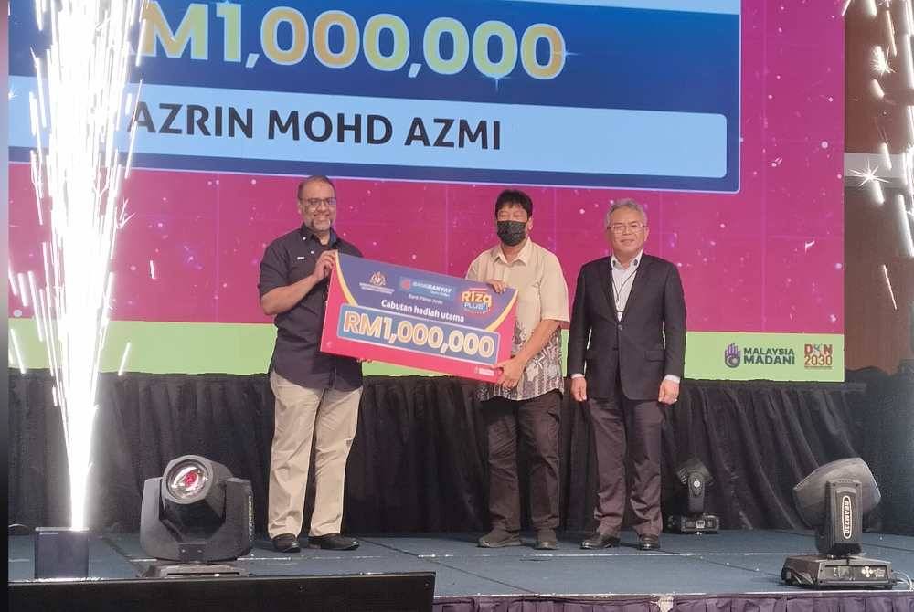 Wakil daripada Azrin (tengah) menerima hadiah utama menerusi Cabutan Hadiah Utama Akaun Pelaburan i-Rizq Plus.