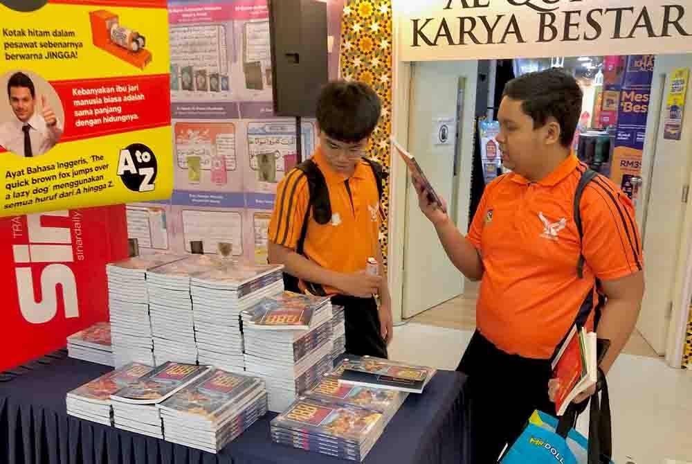 Dua pelajar sekolah dari Sekolah Menengah Subang Utama sedang meneliti buku yang dijual di Jualan Gudang Karangkraf 2024 pada Khamis