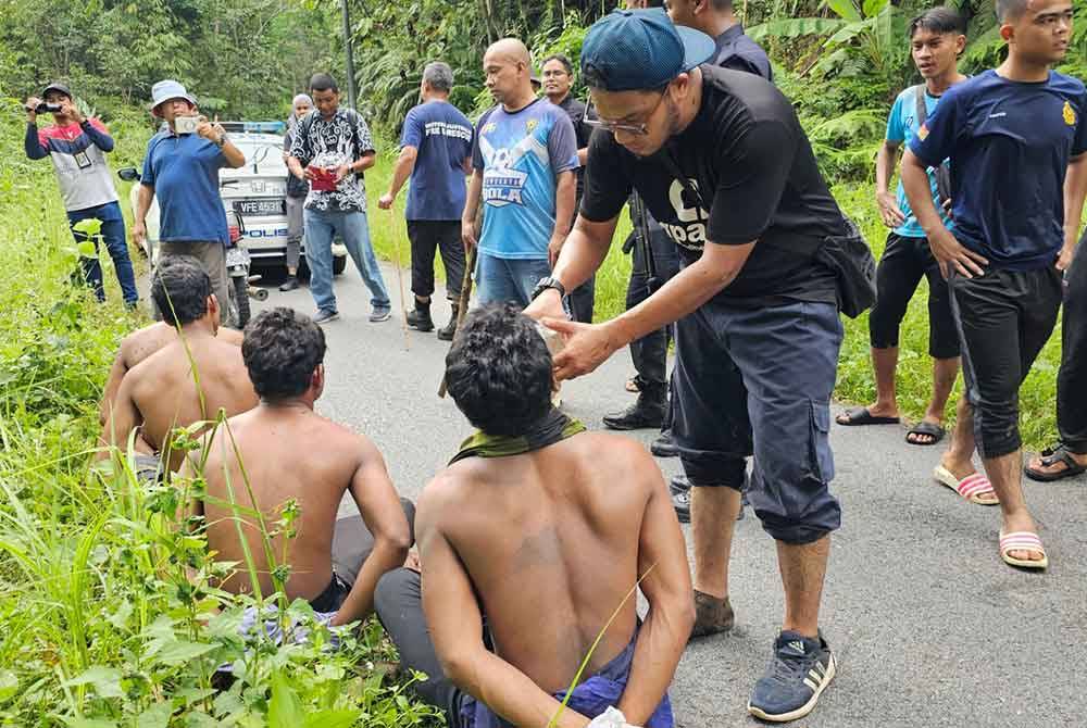 Salah seorang penduduk memberikan air minuman kepada tahanan selepas berjaya dibawa keluar dari hutan.