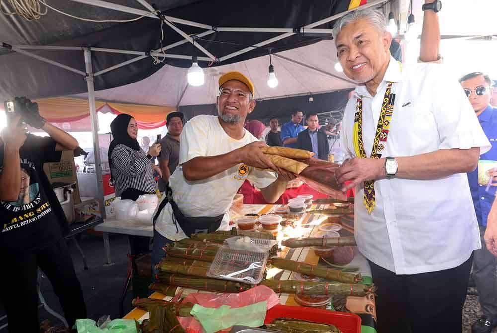 Timbalan Perdana Menteri yang juga Menteri Kemajuan Desa dan Wilayah Datuk Seri Dr Ahmad Zahid Hamidi membeli produk tempatan 'Lemang Sarawak' semasa mengjadiri Majlis Perasmian KUD@Kota Samarahan pada Jumaat. Foto Bernama