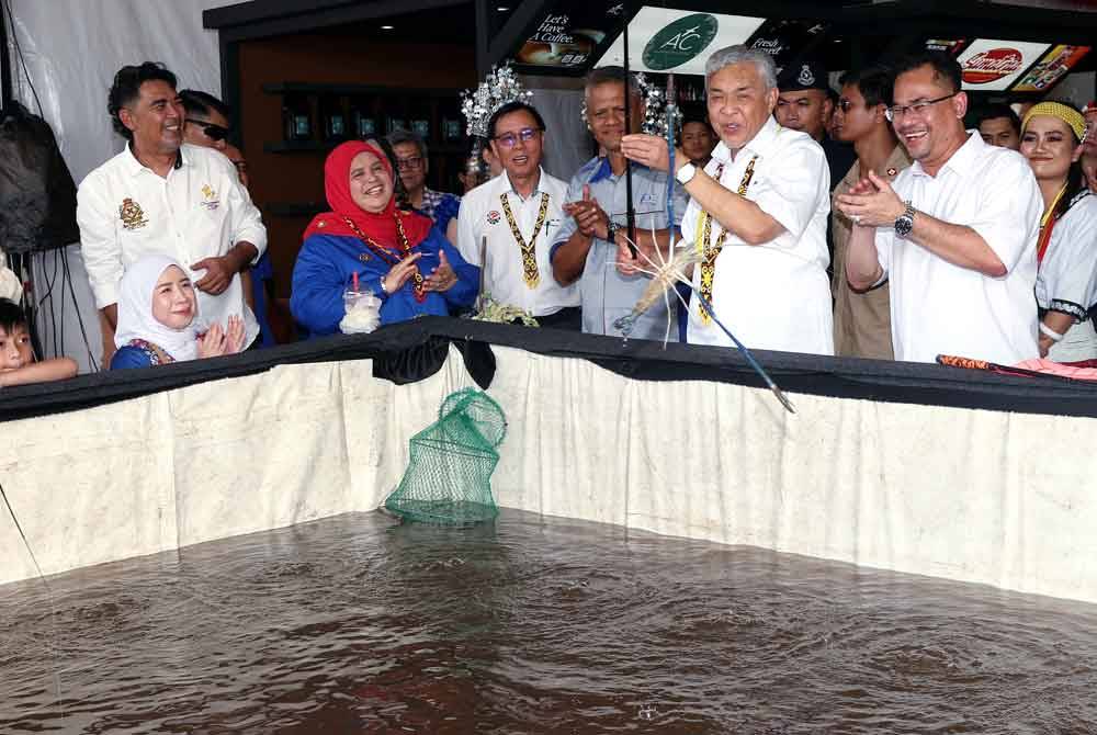 Rubiah ( dua dari kiri) mengiringi Timbalan Perdana Menteri yang juga Menteri Kemajuan Desa dan Wilayah, Datuk Seri Dr Ahmad Zahid Hamidi menunjukkan kemahiran memancing udang galah di Majlis Perasmian KUD@Kota Samarahan hari ini. Foto Bernama