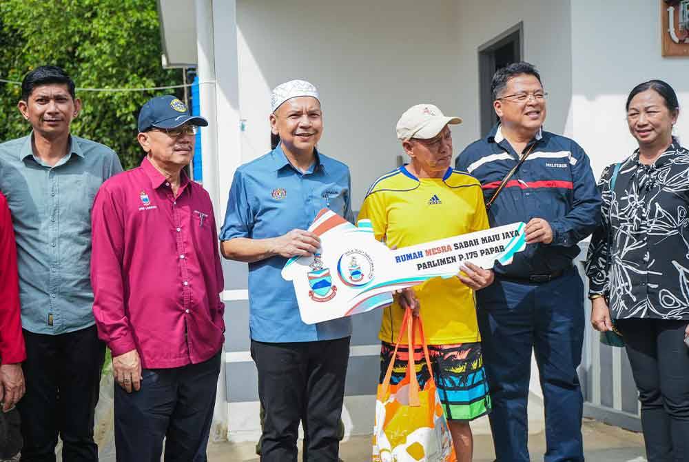 Armizan (empat dari kiri) menyerahkan replika kunci rumah kepada Raymund di Kampung Biau, Papar.