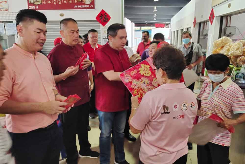 Anthony (tengah) member i kad jemputan rumah terbuka DAP kepada pengunjung Pasar Besar Seremban pada Sabtu.