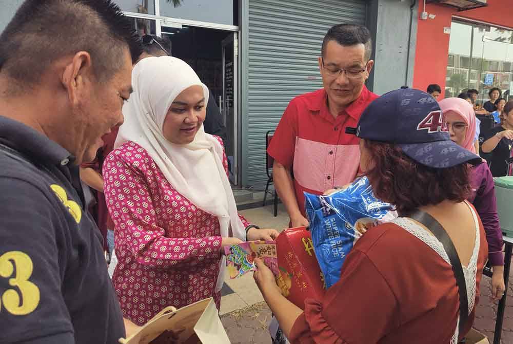 Nurul Syazwani menyampaikan barangan keperluan kepada penerima pada Majlis Penyampaian Sumbangan Tahun Baharu Cina di Pusat Khidmat DUN Permatang, Pasir Penambang di sini pada Sabtu.
