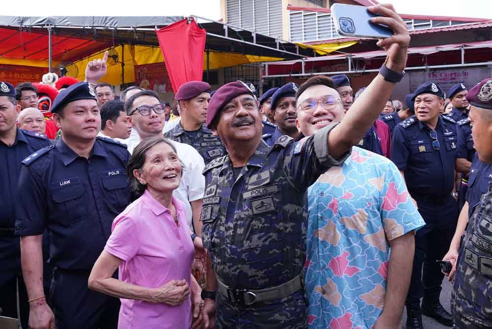 Orang ramai tidak melepaskan peluang bergambar bersama Razarudin ketika program Walkabout Pencegahan Jenayah di Pasar Pandamaran pada Ahad. - FOTO:SINAR HARIAN/ MOHD HALIM ABDUL WAHID