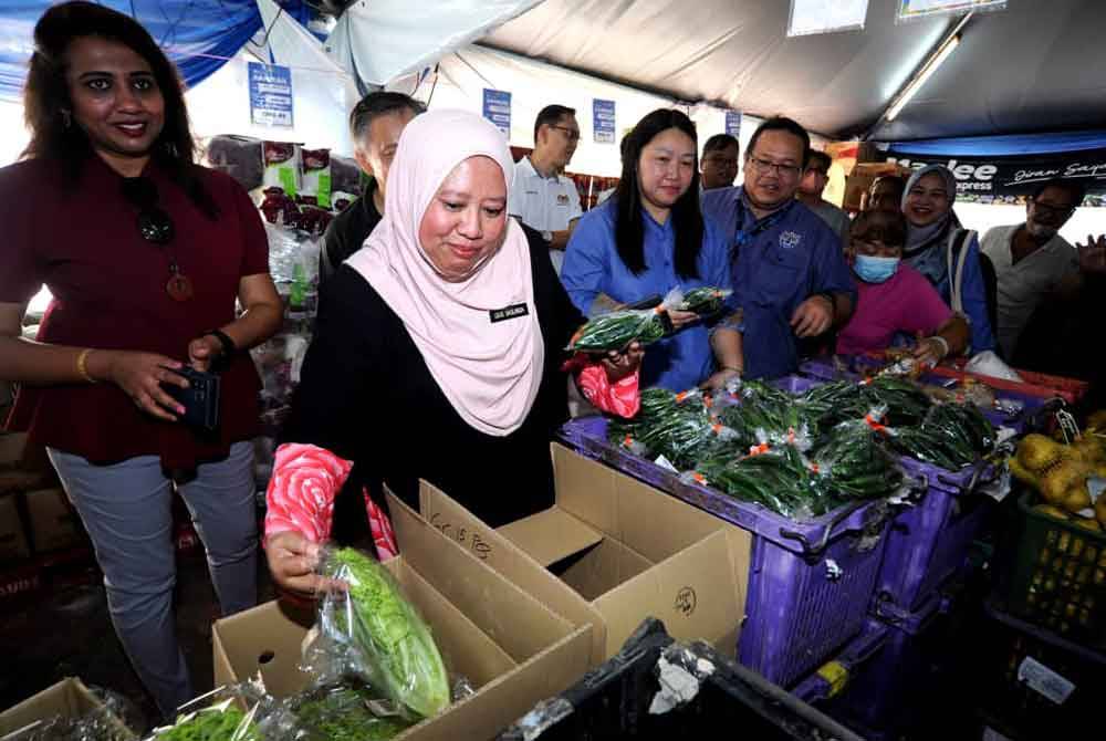 Lilis Saslinda melihat sayuran yang dijual sempena Jualan Rahmah Tahun Baharu Cina di Block 56 flat Taman Ungku Tun Aminah, Johor Bahru pada Sabtu