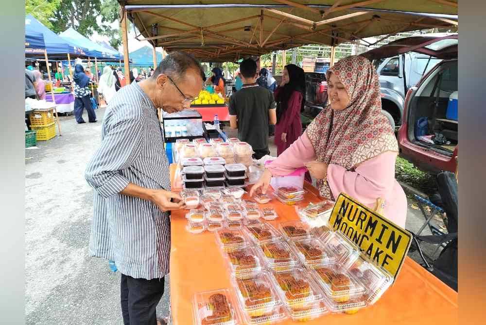 Nur Solihah melayani pelanggan dari pelbagai kaum yang datang membeli kuih bulan yang dijual di Pasar Tani Padang Hiliran, Kuala Terengganu.
