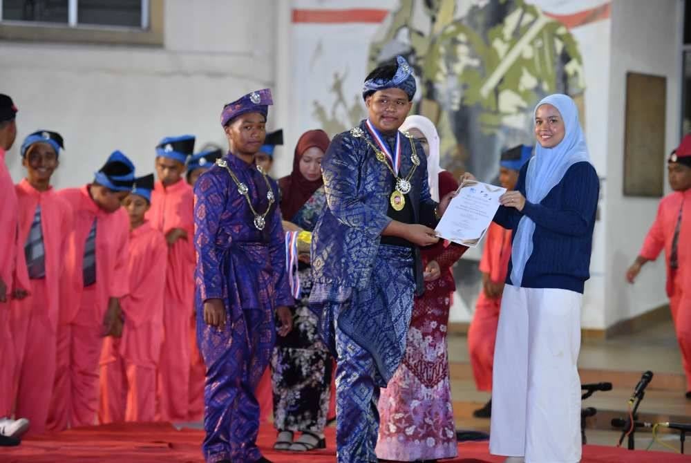 Muhammad Rafie (tengah) menerima sijil penyertaan dan hadiah disampaikan Suriati sempena majlis penutup bengkel yang diadakan di Dataran Kompleks Sanggar Siswa, Bangunan Hal Ehwal Pelajar dan Alumni (HEPA), Universiti Malaysia Terengganu pada Isnin.