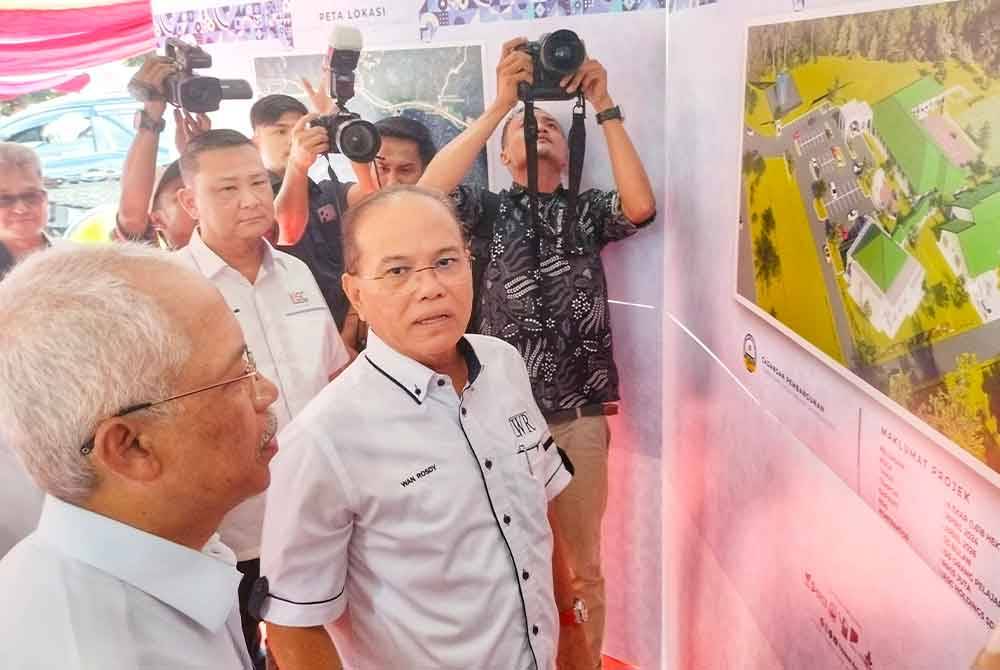 Wan Rosdy (tengah) ketika mendengar penerangan daripada Mahmud (kanan) mengenai tapak projek MTNP Cawangan Lipis