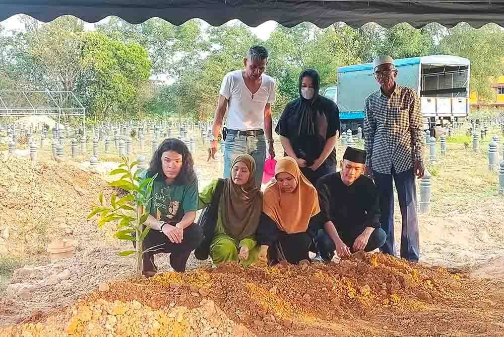 Anak-anak arwah dari kiri Mohd Firdaus, Azreyna Khor dan Siti Fairuz di sisi kubur arwah di Tanah Perkuburan Taman Uda pada Khamis.
