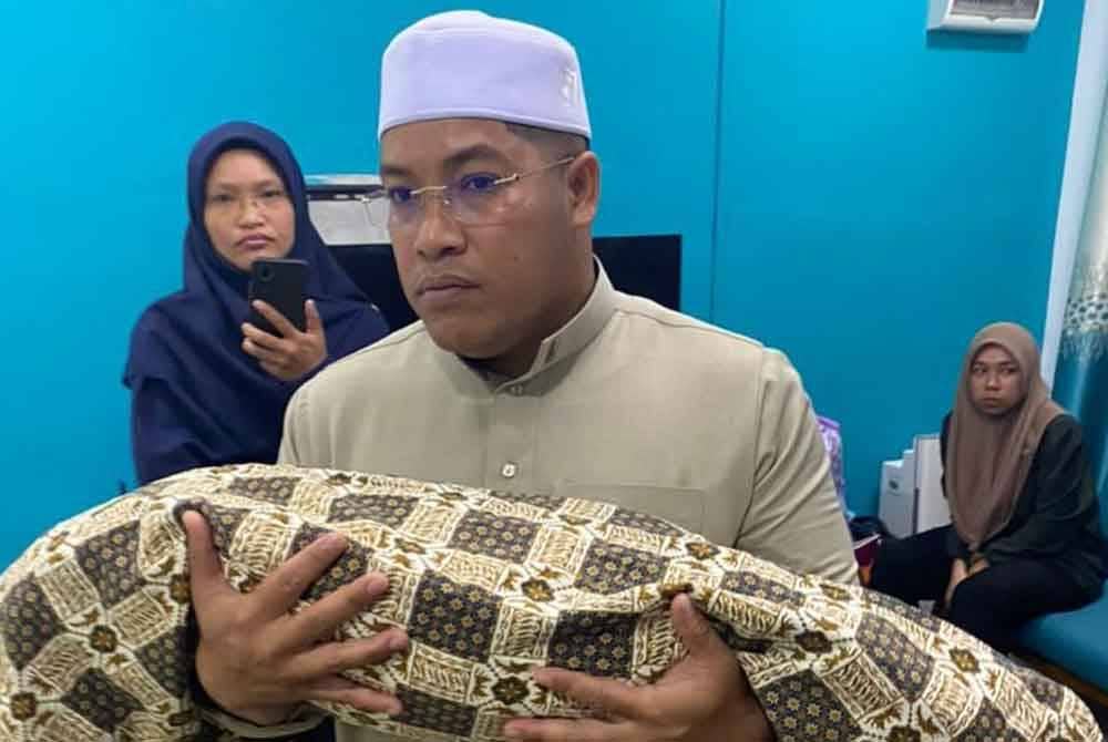 Mohd Shafiq membawa jenazah anaknya untuk dikebumikan.