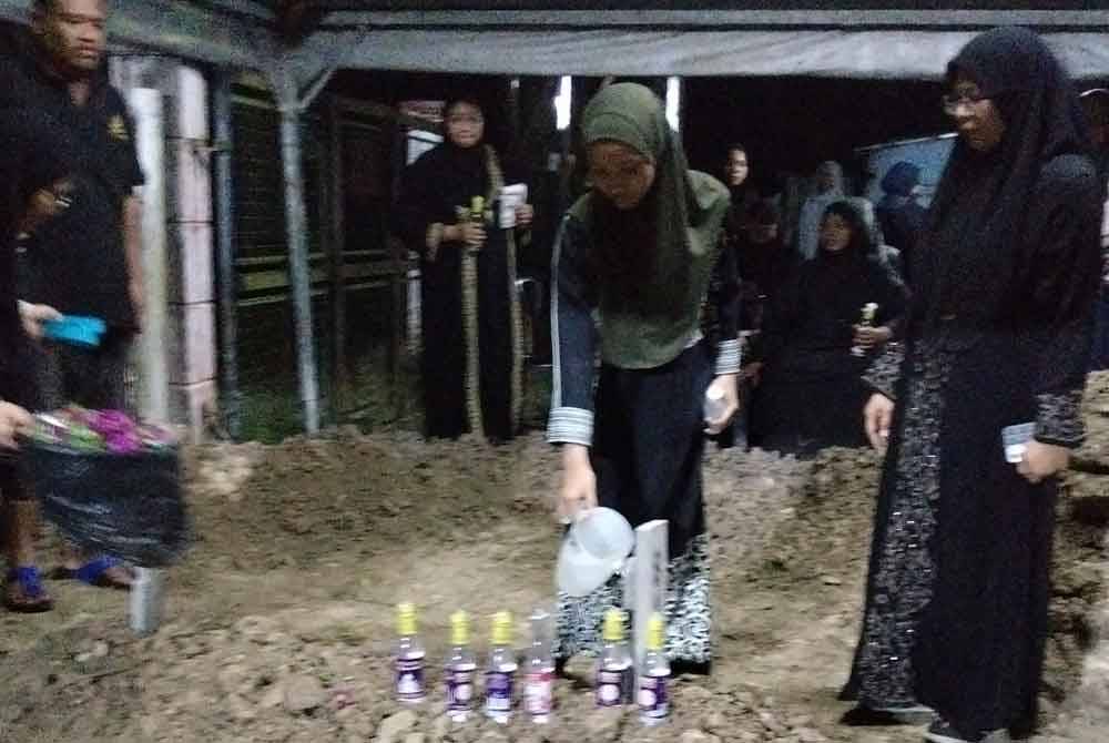 Anak perempuan Allahyarham, Safiyyah Umairah menyiram air mawar.