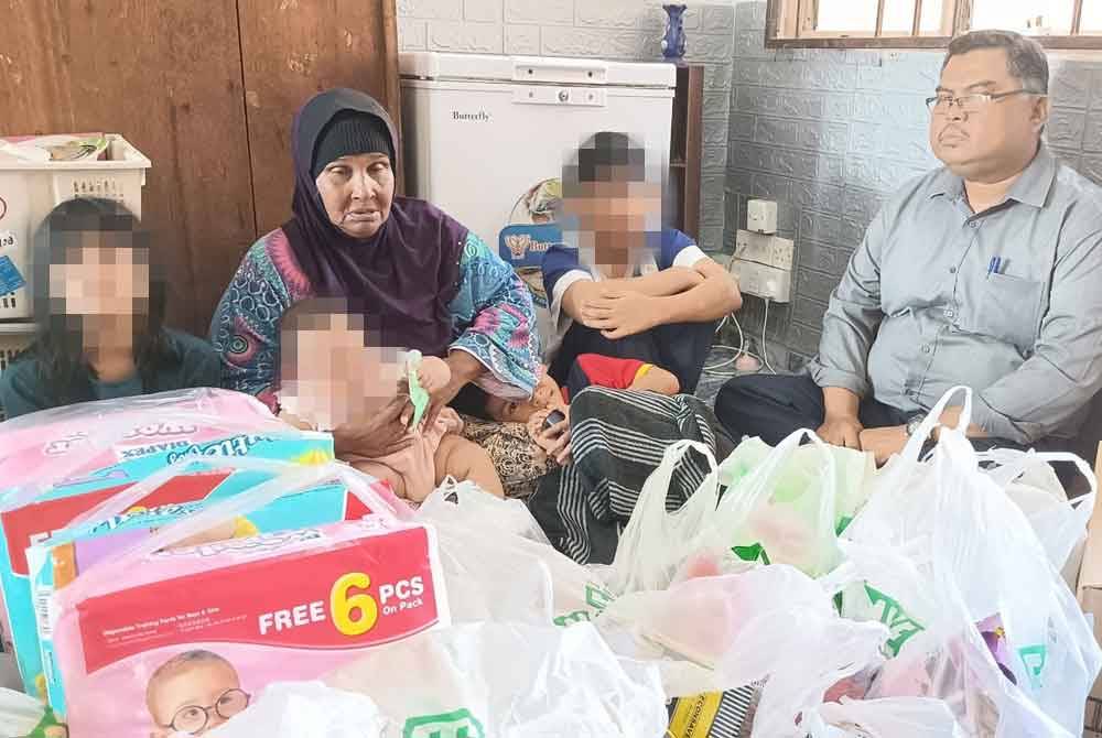 Mas Imran (kanan) menyampaikan sumbangan kepada Normah di rumahnya di PPR Kempas Permai, Johor Bahru pada Jumaat.