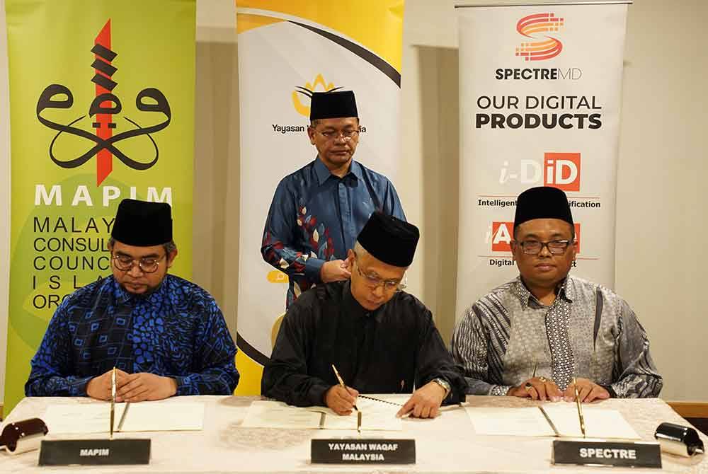Mohd Na'im memerhatikan ketiga-tiga wakil daripada Mapim, YWM dan Spectre MD Sdn Bhd menandatangani memorandum persefahaman.