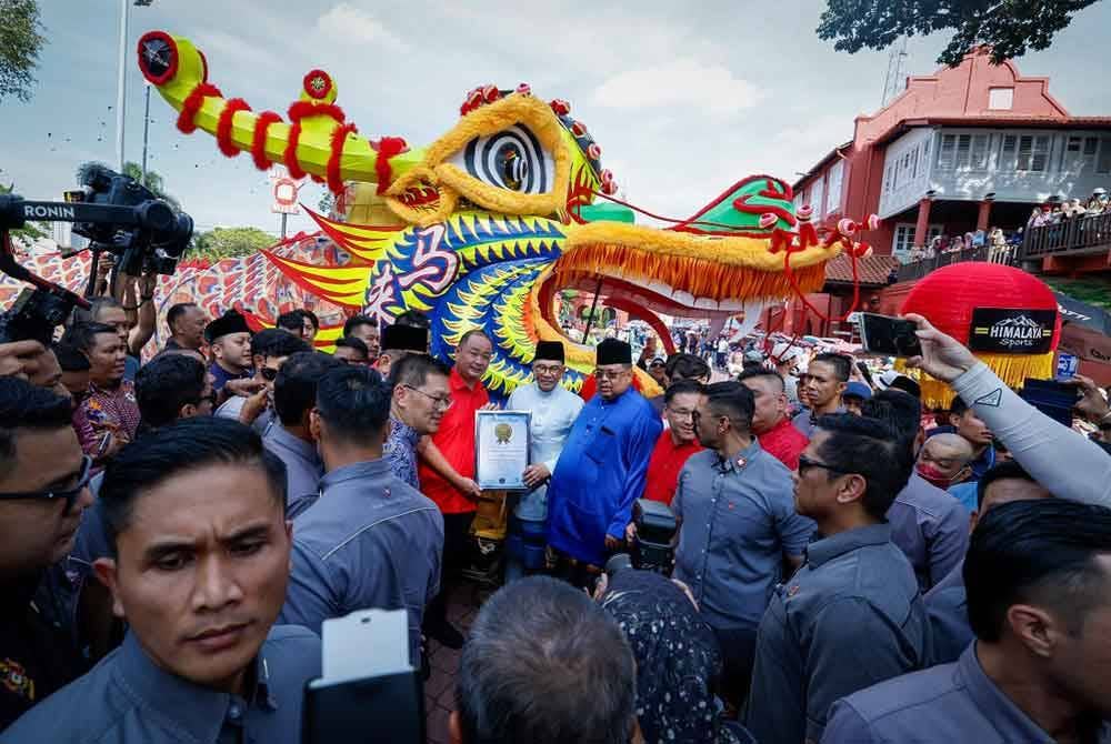 Anwar (tengah) bersama Ab Rauf (kanan) bergambar kenangan di hadapan arca kepala naga gergasi semasa mengadakan tinjauan mesra di sekitar Bangunan Merah dan Jonker Walk pada Jumaat. - Foto Bernama