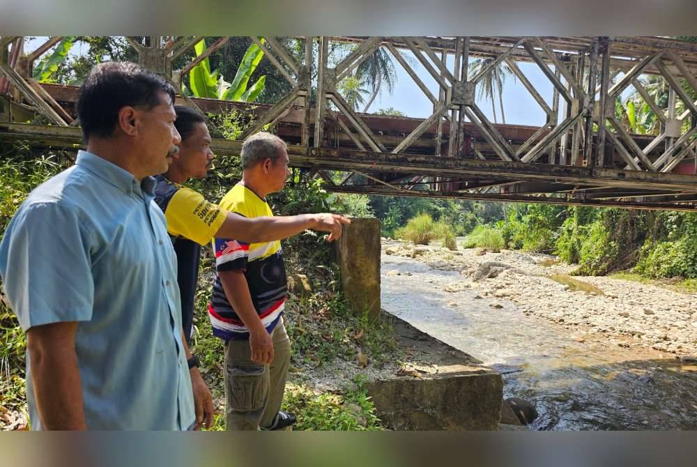 Wahiddin (kiri) bersama penduduk menunjukkan lokasi tragedi kepala air yang meragut empat nyawa, Rabu lalu.
