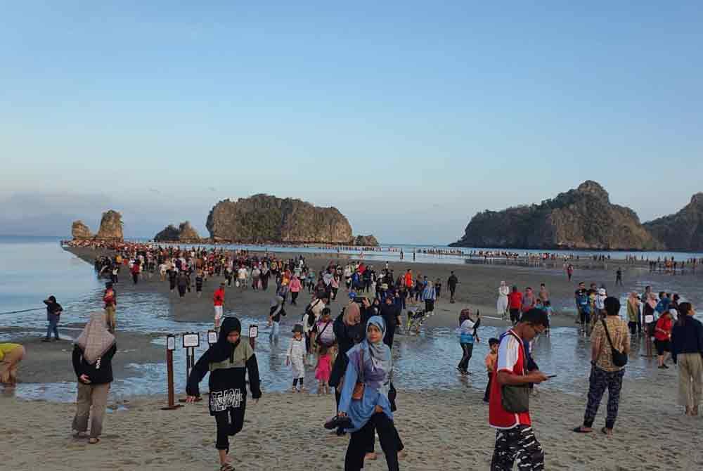 Pengunjung tidak melepaskan peluang berjalan atas beting pasir sejauh 600 m yang muncul selepas fenomena laut terbelah di Langkawi, pada Ahad.