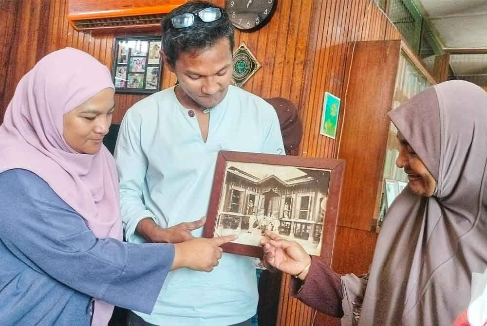 Anisah (kanan) bersama adik-adiknya, Idham dan Samira, 50, bersama gambar rumah tersebut yang menjadi sejarah peninggalan berharga buat generasi keluarga tersebut.