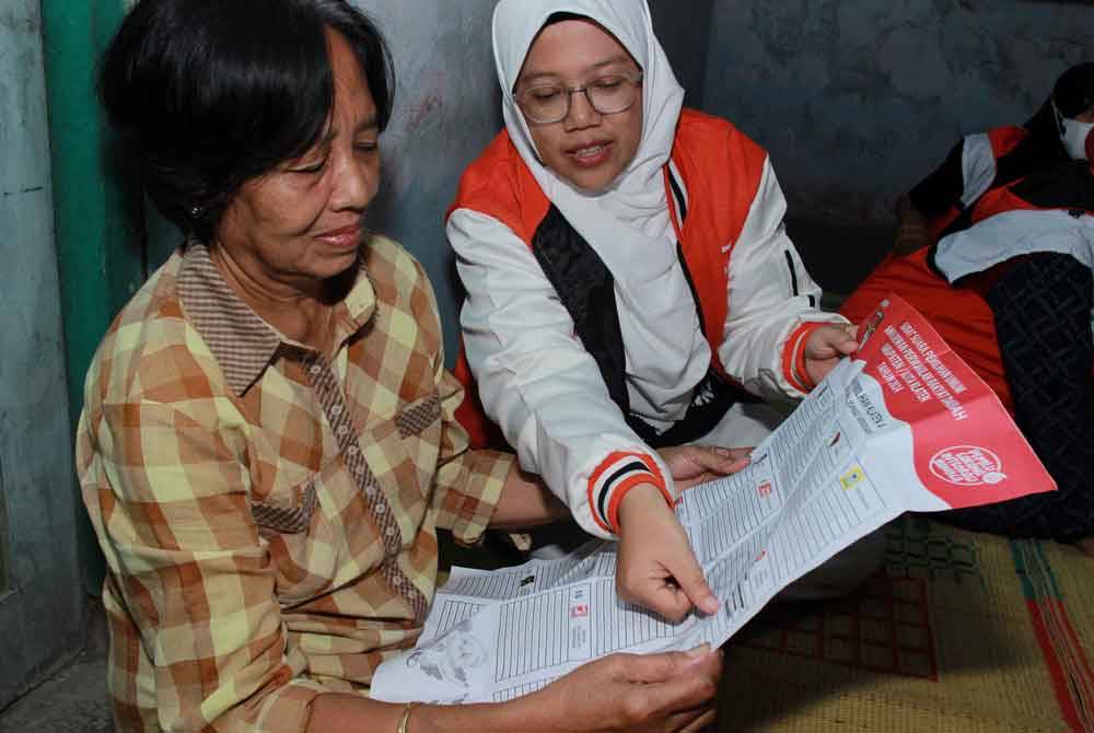 Lingga Permesti (kanan) mewakili Parti Keadilan Sejahtera (PKS) memberi penerangan tentang cara mengundi ketika mengunjungi penduduk di Klaten, Jawa Tengah.