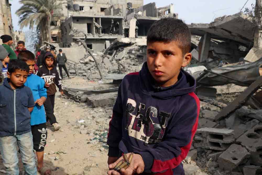 Seorang kanak-kanak Palestin memegang kelongsong peluru yang digunakan tentera Israel untuk menyerang Rafah pada Selasa. - AFP