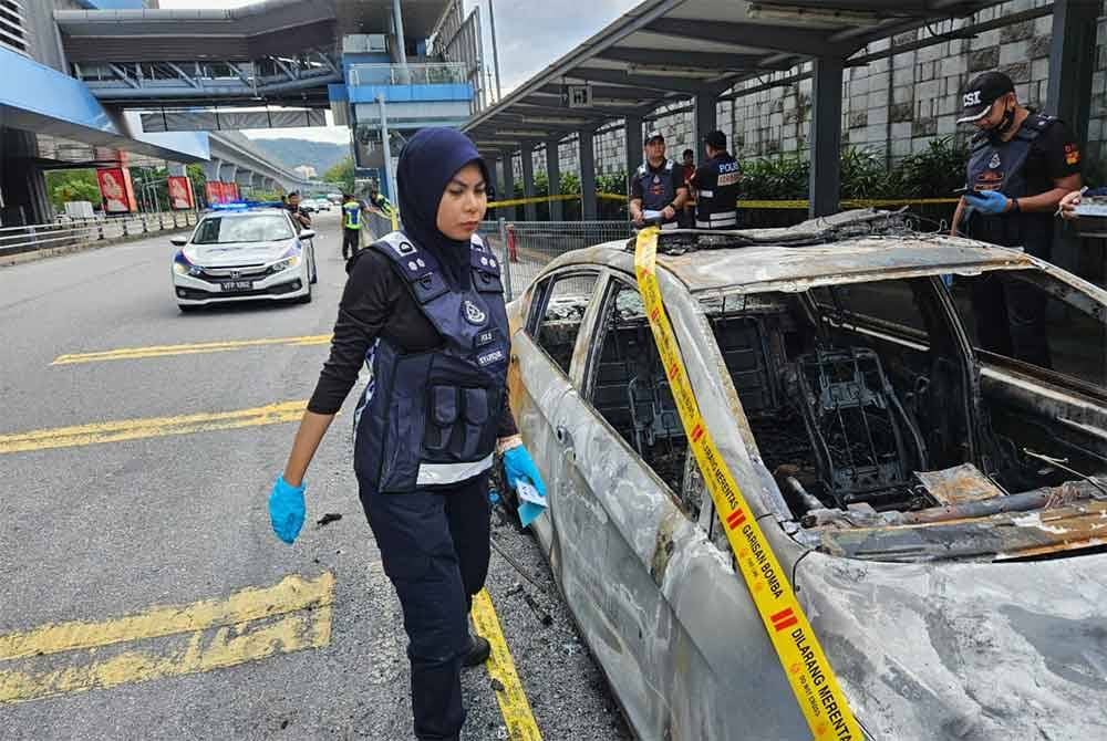 Anggota polis berada di lokasi kejadian bagi menyiasat kes bakar kereta polis bantuan di MRT Mutiara Damansara, Petaling Jaya, Selangor pada Khamis. - Foto: PDRM