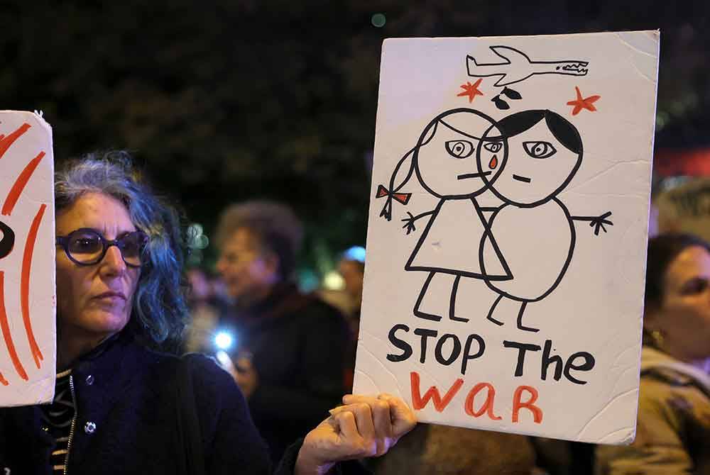 Seorang penunjuk perasaan memegang sepanduk semasa demonstrasi menentang kerajaan Perdana Menteri Netanyahu di dataran Habima di Tel Aviv. Foto EPA